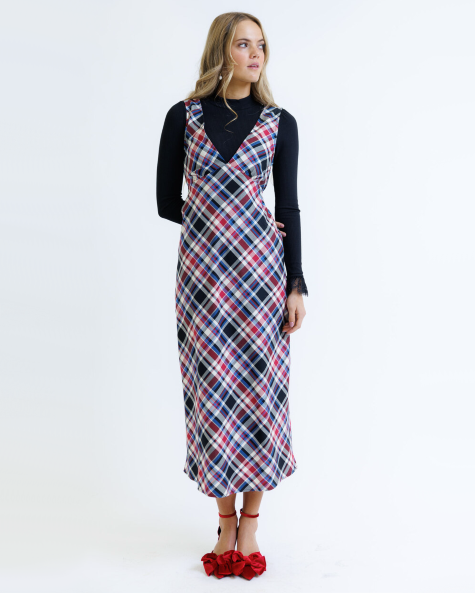 Woman wearing a plaid dress over a black top on a white background