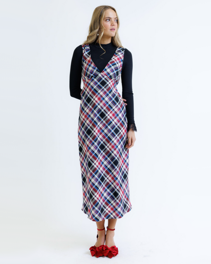 Woman wearing a plaid dress over a black top on a white background