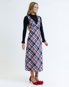 Woman wearing a plaid dress over a black top on a white background