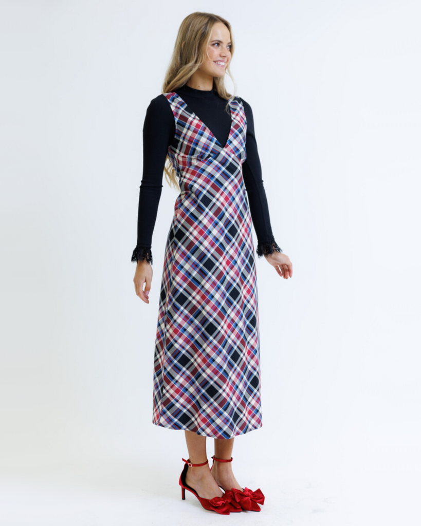 Woman wearing a plaid dress over a black top on a white background