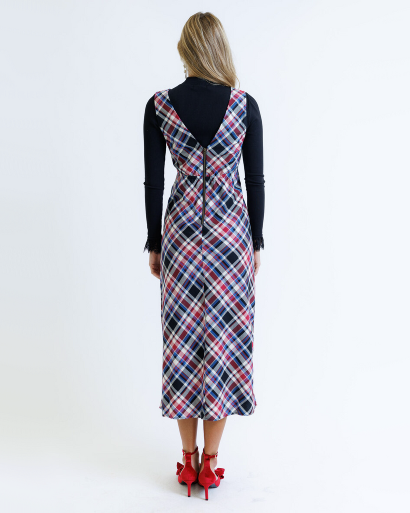 Woman wearing a plaid dress over a black top on a white background