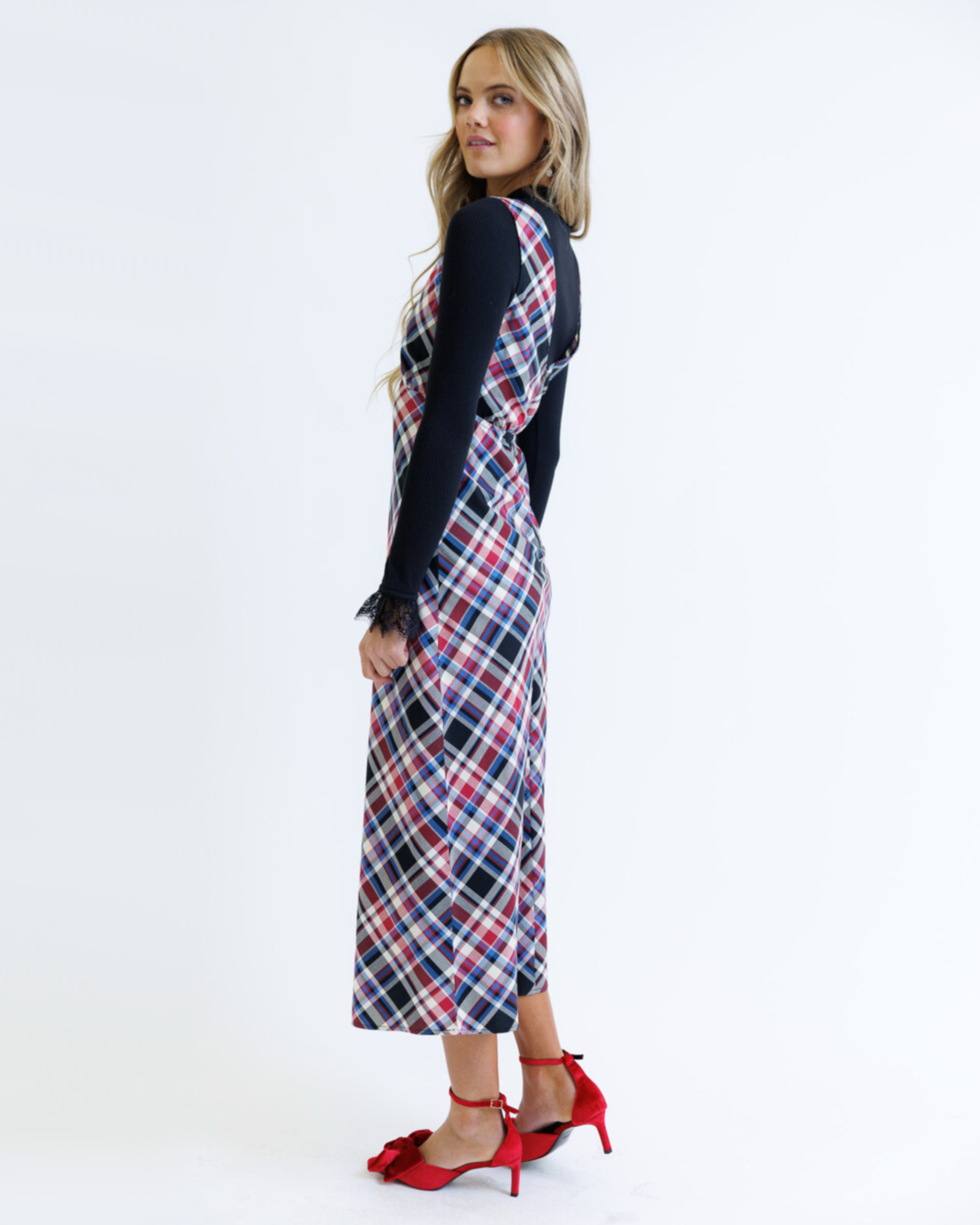 Woman wearing a plaid dress over a black top on a white background