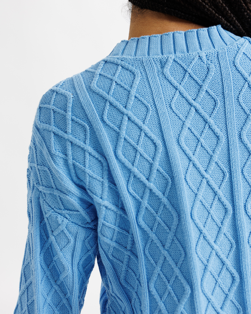 Close-up of a blue cable knit sweater on a white background