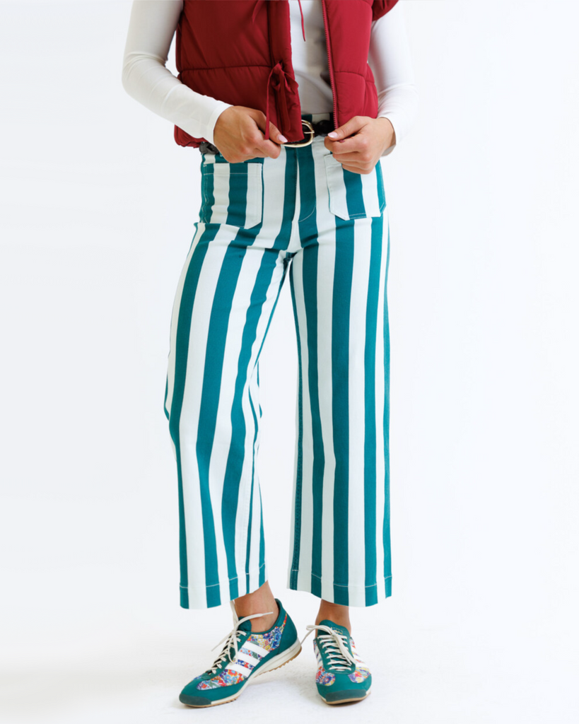 Woman wearing a red puffer vest and green striped pants on a white background