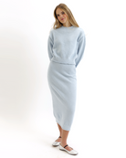 Woman wearing a light blue knitted sweater and skirt set on a white background
