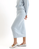 Woman wearing a light blue knitted sweater and skirt set on a white background