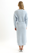 Woman wearing a light blue knitted sweater and skirt set on a white background