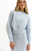 Woman wearing a light blue knitted sweater and skirt set on a white background