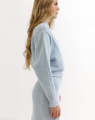 Woman wearing a light blue knitted sweater and skirt set on a white background