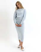 Woman wearing a light blue knitted sweater and skirt set on a white background