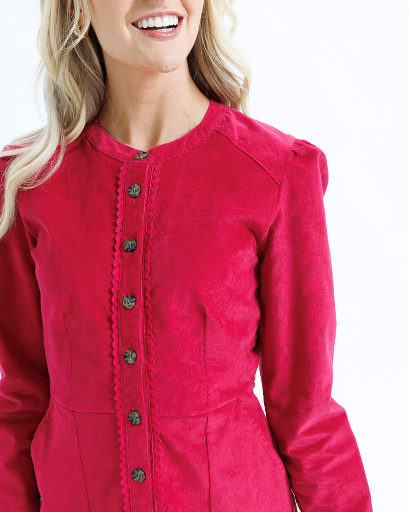 Red dress with black buttons worn by a woman on a white background
