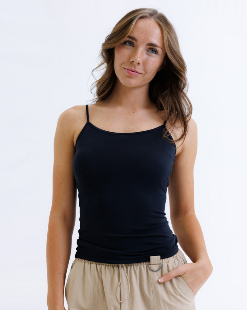 Woman wearing a black layering tank top against a white background