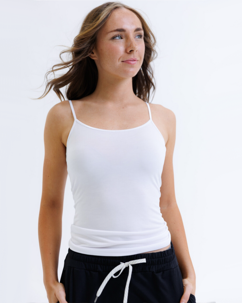 Woman wearing a white layering tank top against a white background