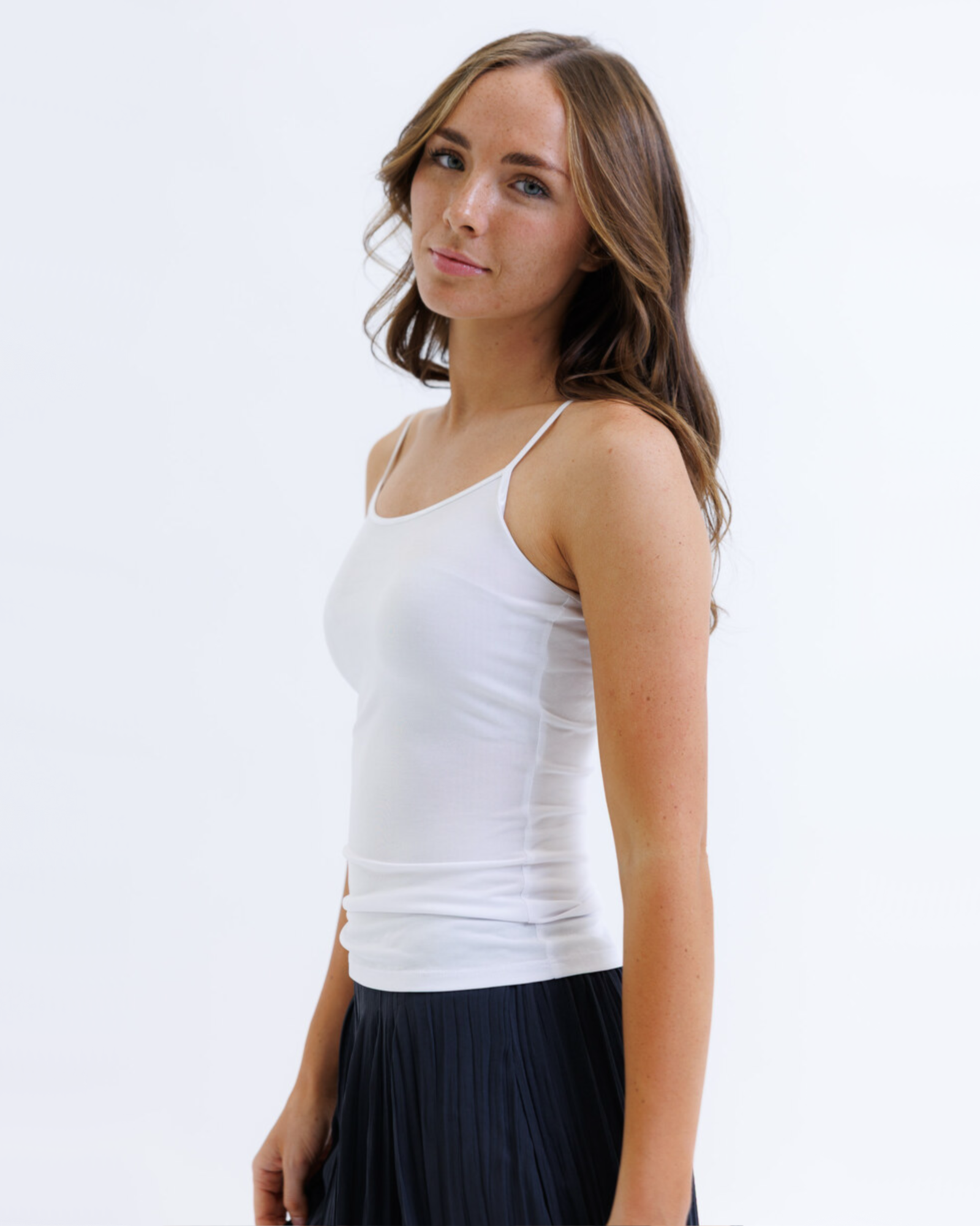 Woman wearing a white layering tank top against a white background