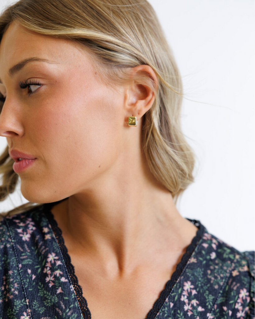 Close-up of a woman wearing gold earrings on a white background