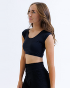 Woman wearing a black cropped layering top and black pants on a white background