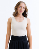 Woman wearing a nude layering tank top and black skirt on a white background