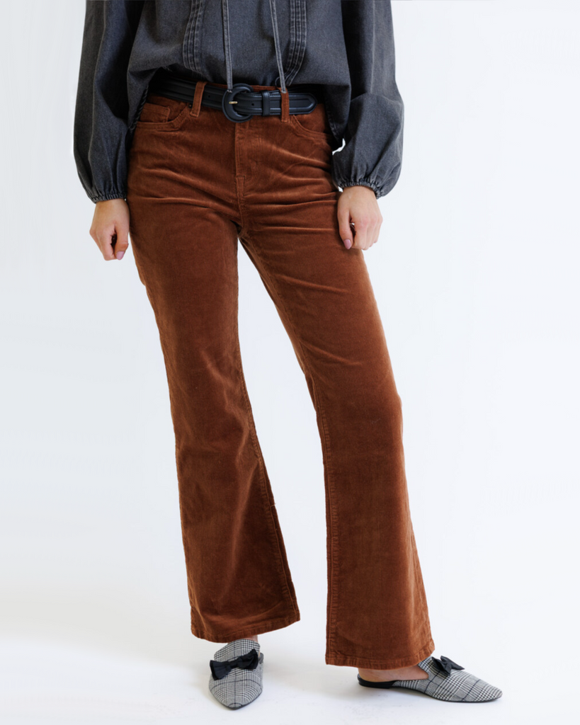 Woman wearing brown corduroy jeans on a white background