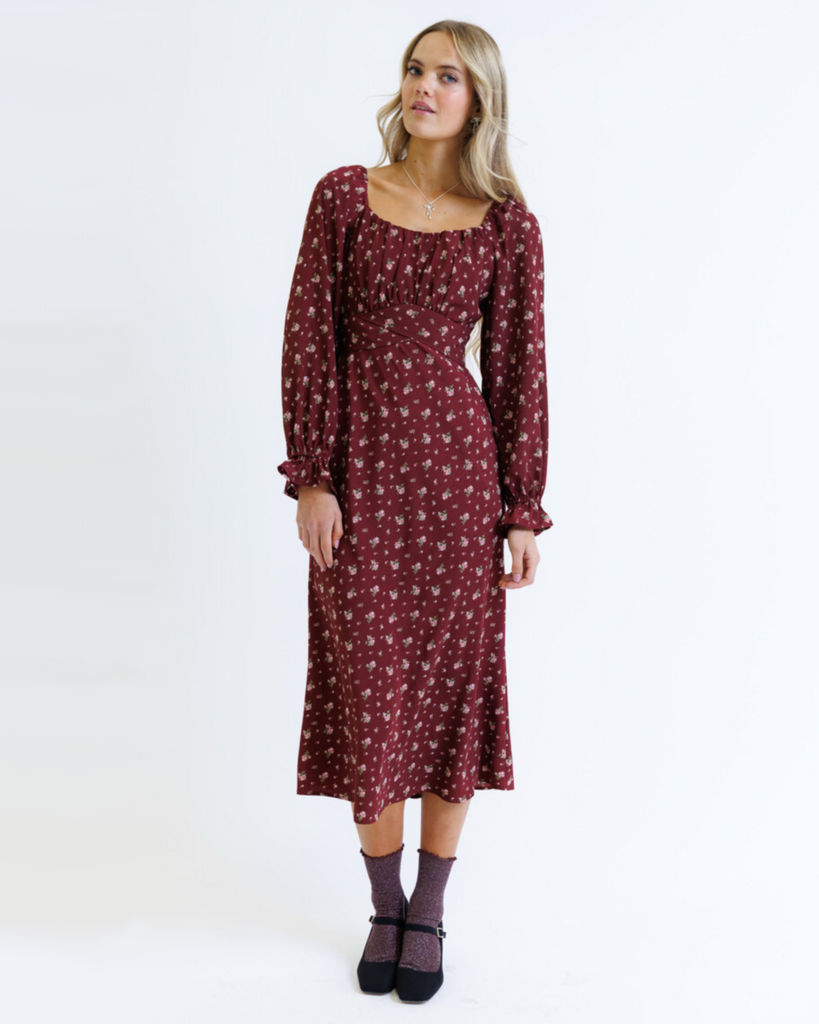 Woman wearing a burgundy floral dress on a white background