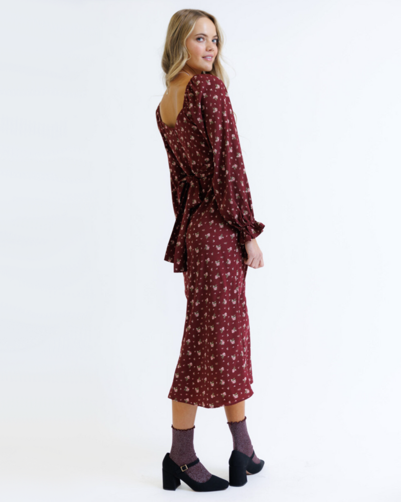 Woman wearing a burgundy floral dress on a white background