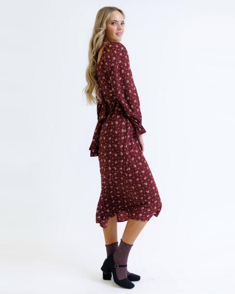Woman wearing a burgundy floral dress on a white background