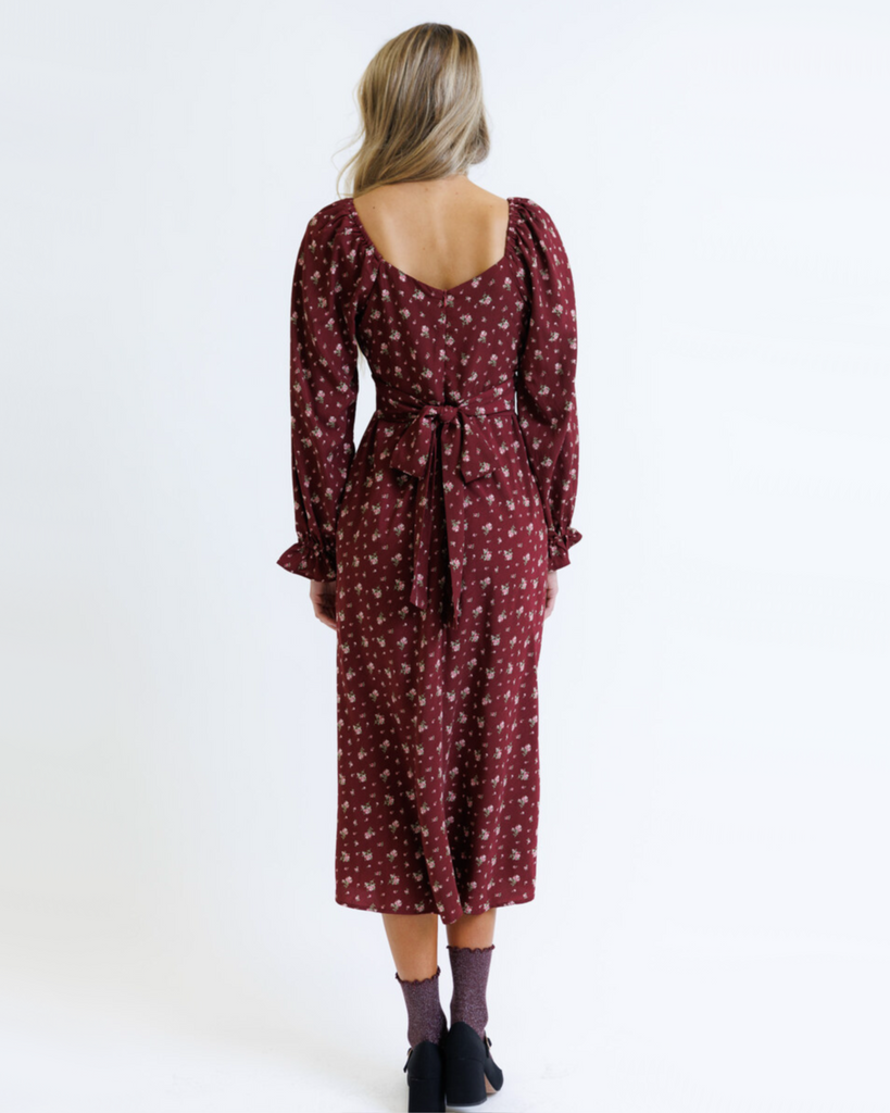 Woman wearing a burgundy floral dress on a white background