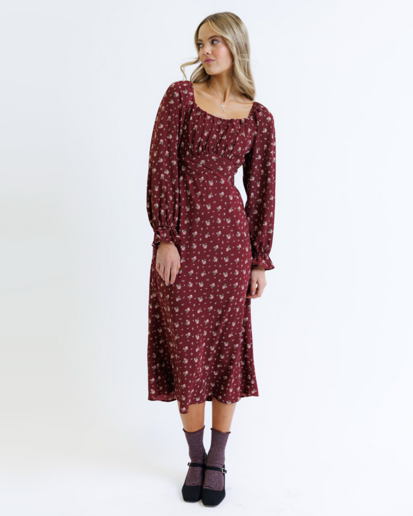 Woman wearing a burgundy floral dress on a white background