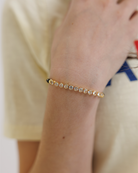 Gold bracelet with cubic zirconia stones on a wrist against a blurred background