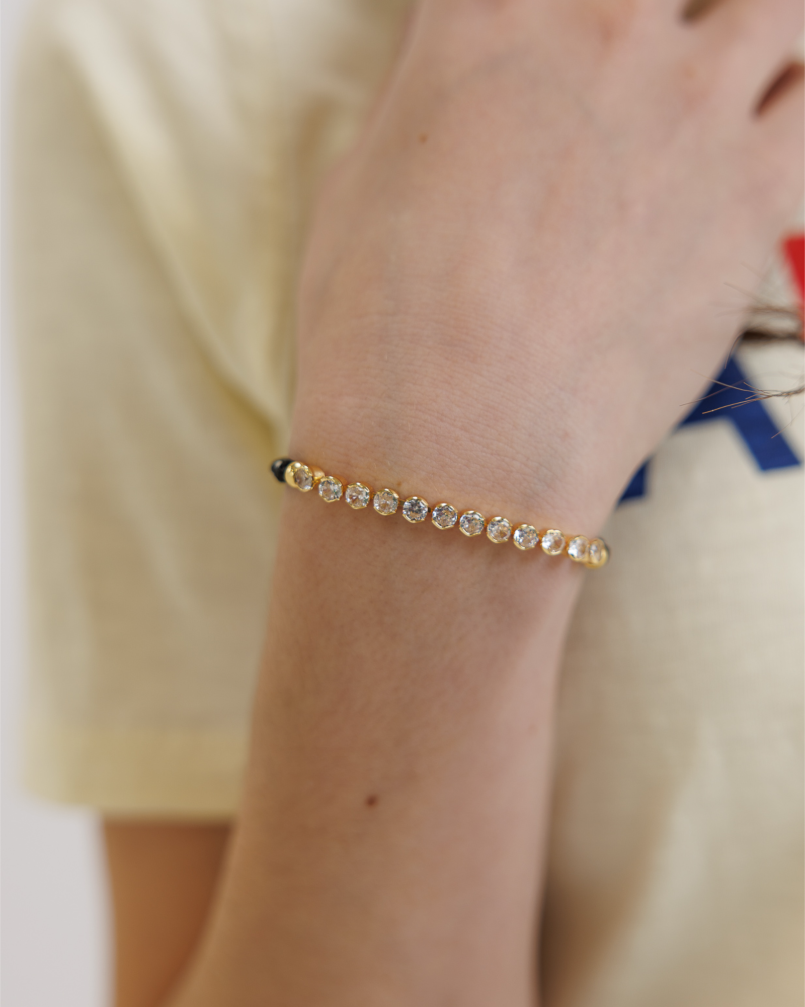 Gold bracelet with cubic zirconia stones on a wrist against a blurred background