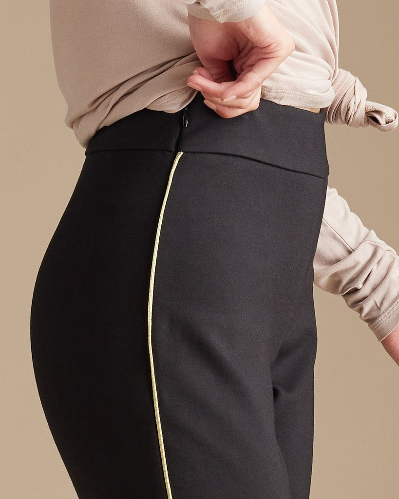 Woman in black leggings with gold piping along sides