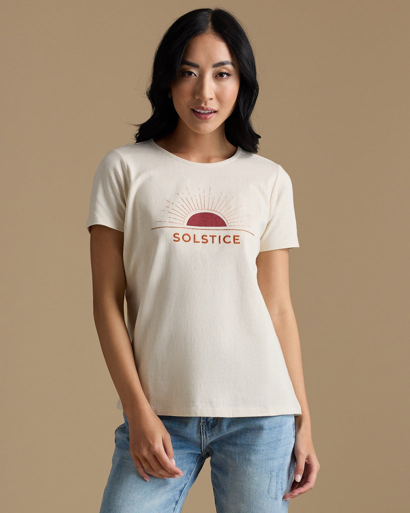 Woman in a tan graphic tee that says "solstice"