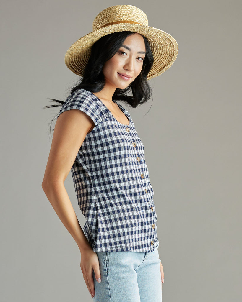 Woman in a navy and white gingham blouse with short sleeves and buttons down the front