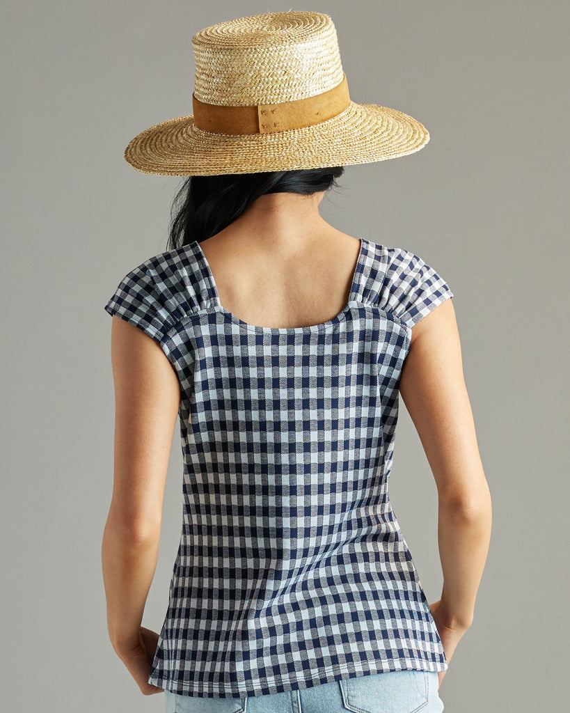 Woman in a navy and white gingham blouse with short sleeves and buttons down the front