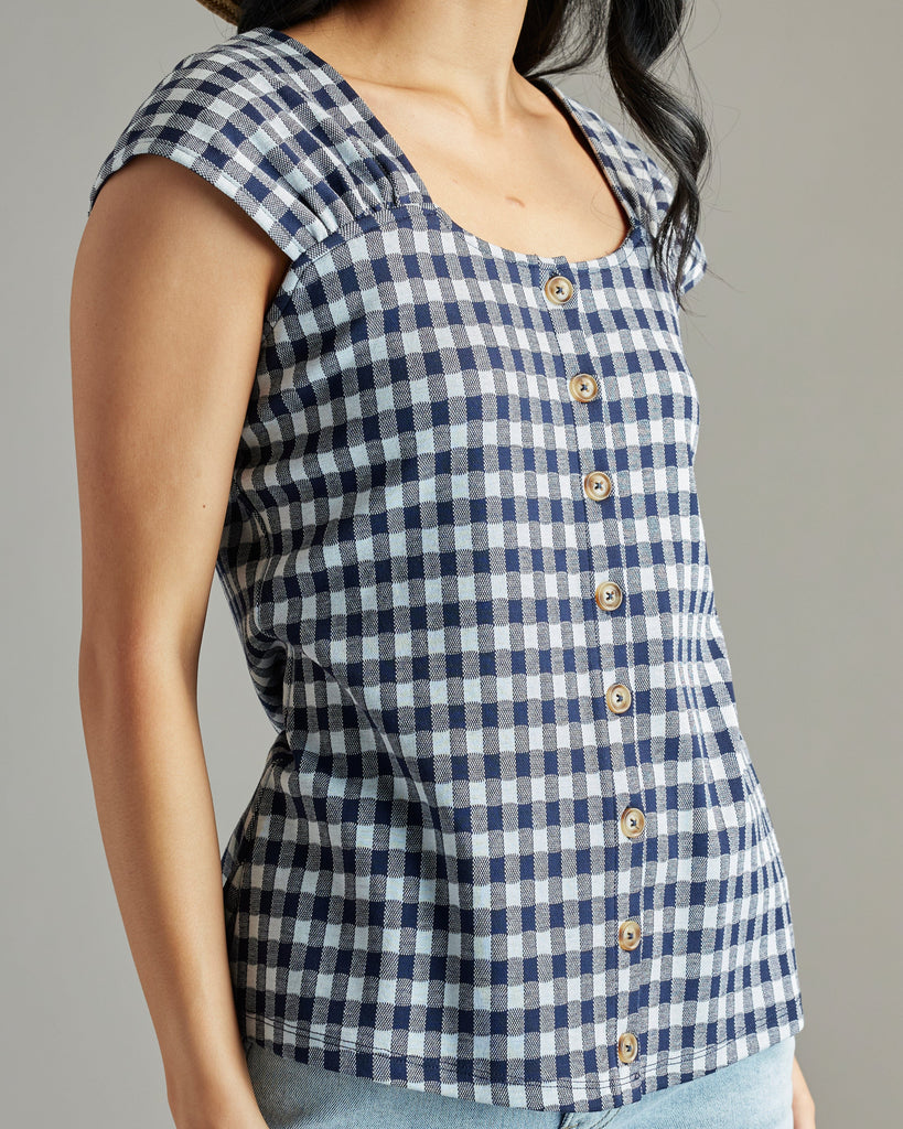 Woman in a navy and white gingham blouse with short sleeves and buttons down the front