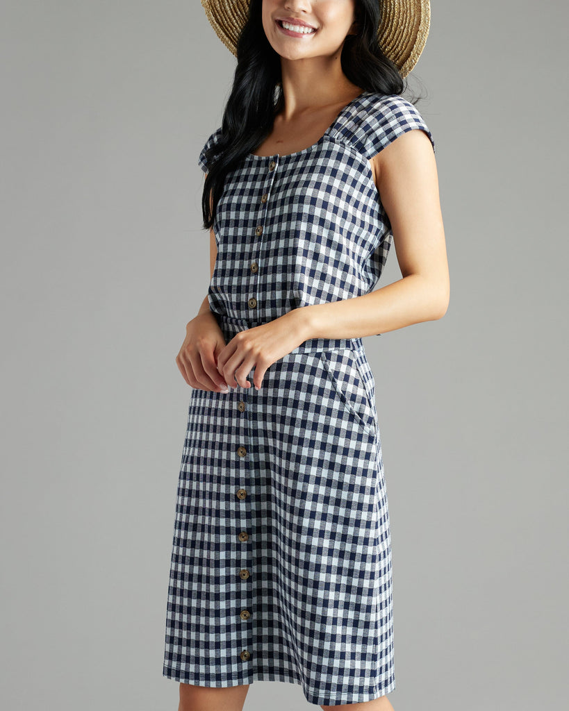 Woman in a navy and white gingham blouse with short sleeves and buttons down the front