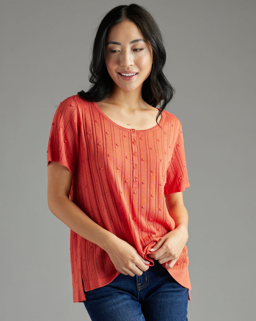 Woman in orange short sleeve textured sweater