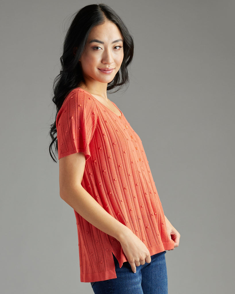 Woman in orange short sleeve textured sweater