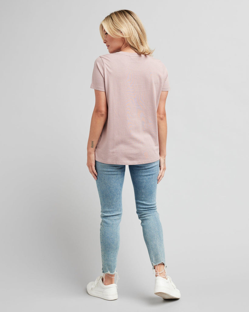 Woman in a short sleeve, pink graphic tee with a silver design on front