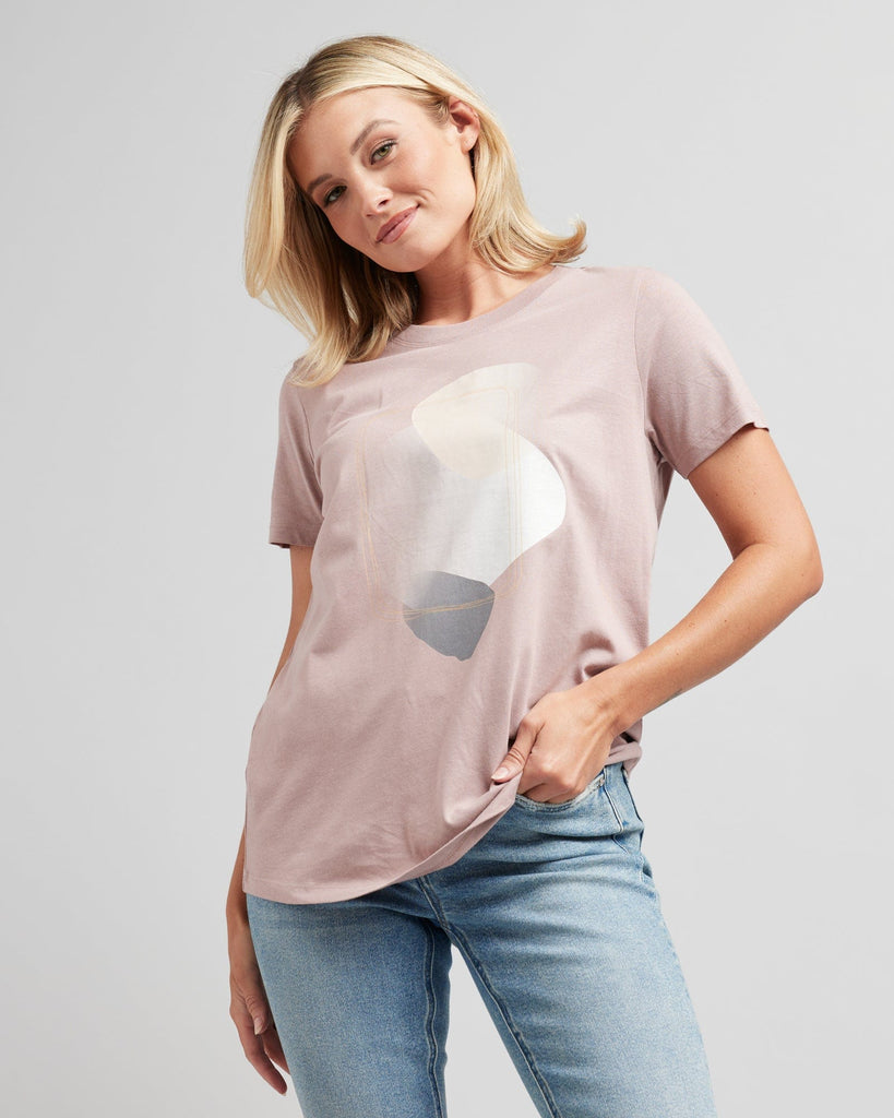 Woman in a short sleeve, pink graphic tee with a silver design on front