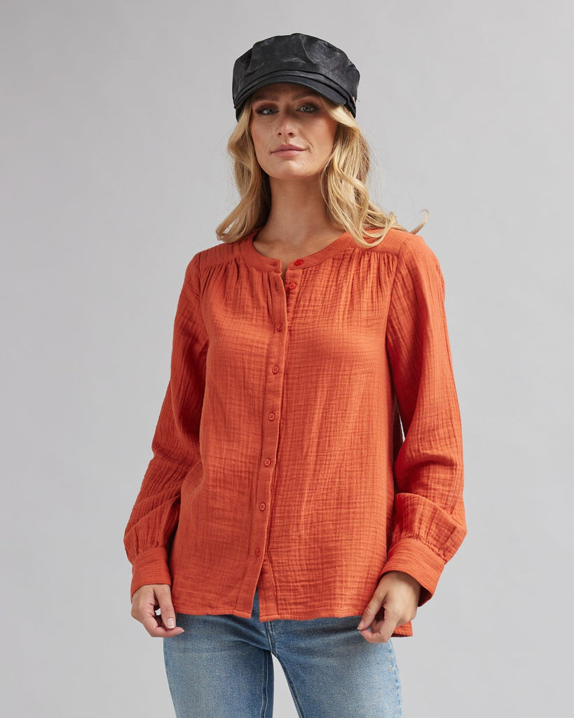 Woman in a long sleeve, orange, textured blouse