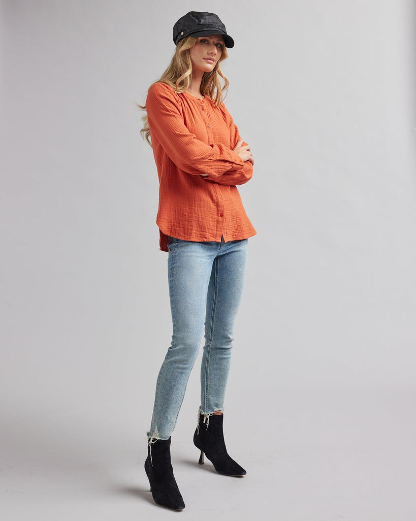 Woman in a long sleeve, orange, textured blouse