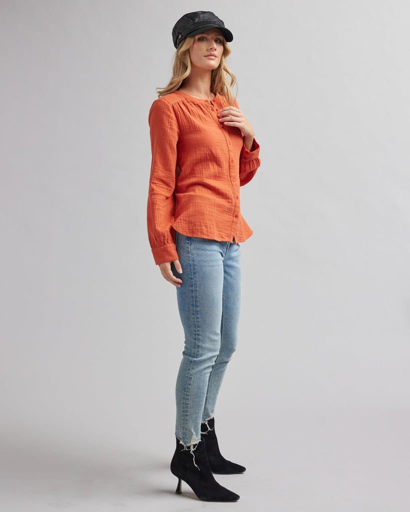 Woman in a long sleeve, orange, textured blouse