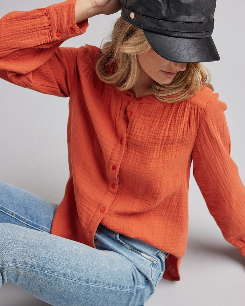 Woman in a long sleeve, orange, textured blouse