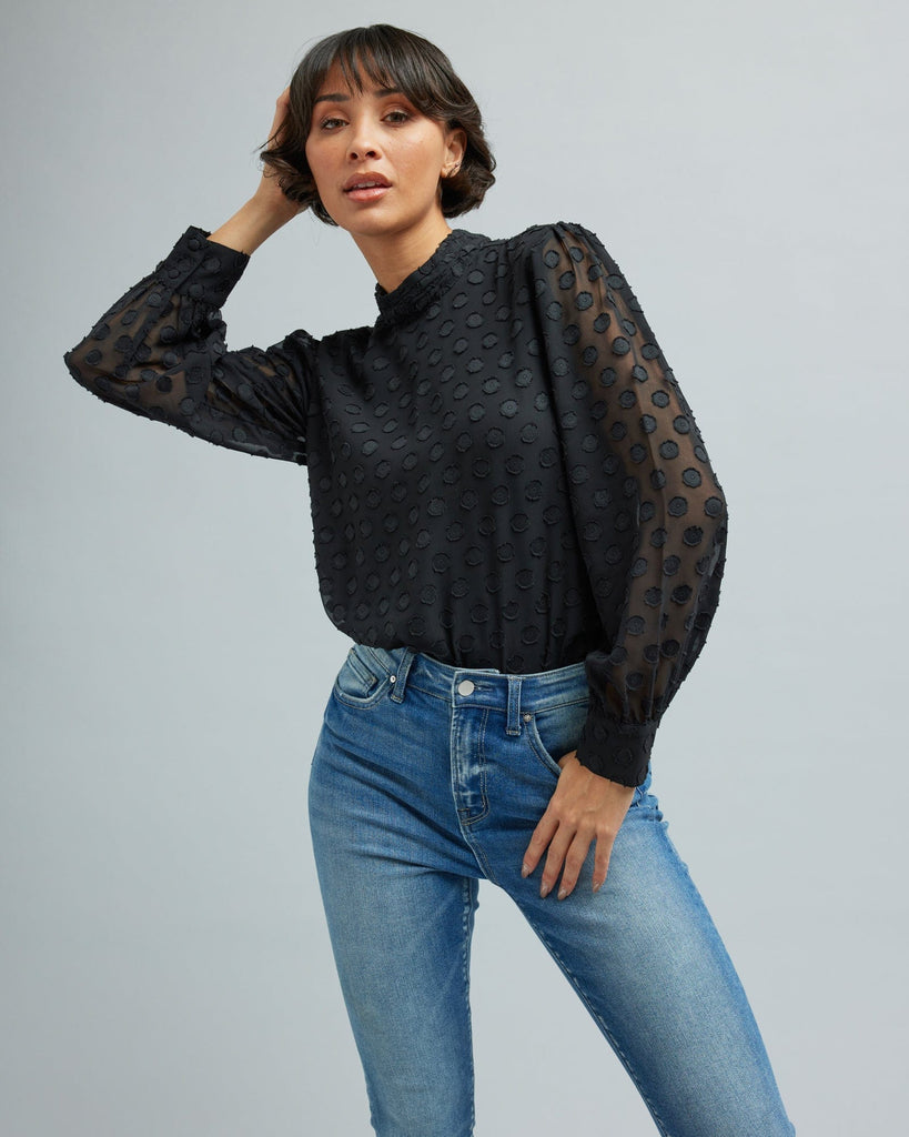 Woman in a long sleeve, black, blouse with polka dots