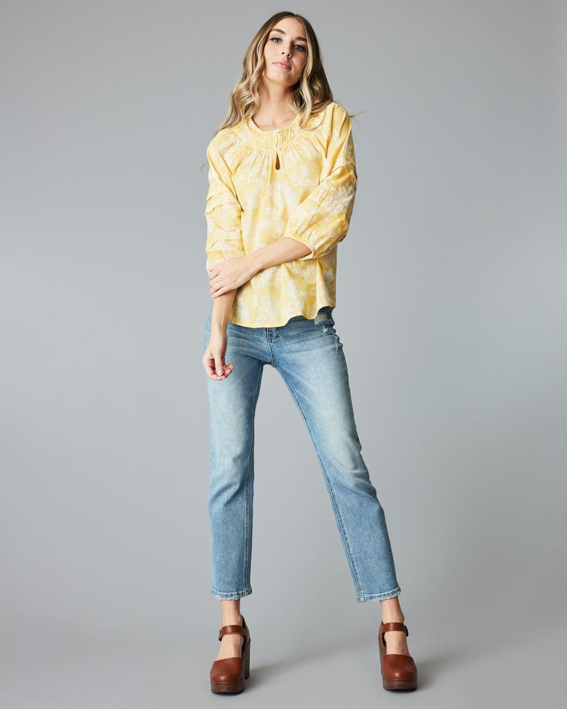 Woman in a 3/4 sleeve, yellow blouse.