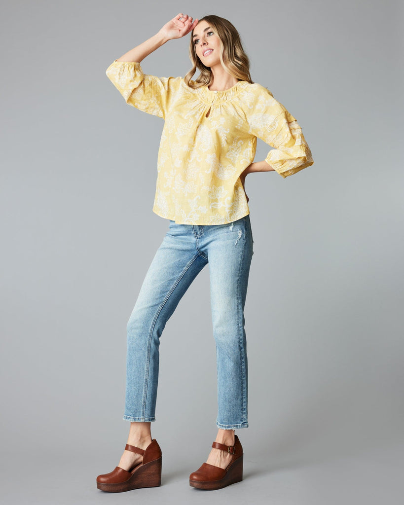 Woman in a 3/4 sleeve, yellow blouse.