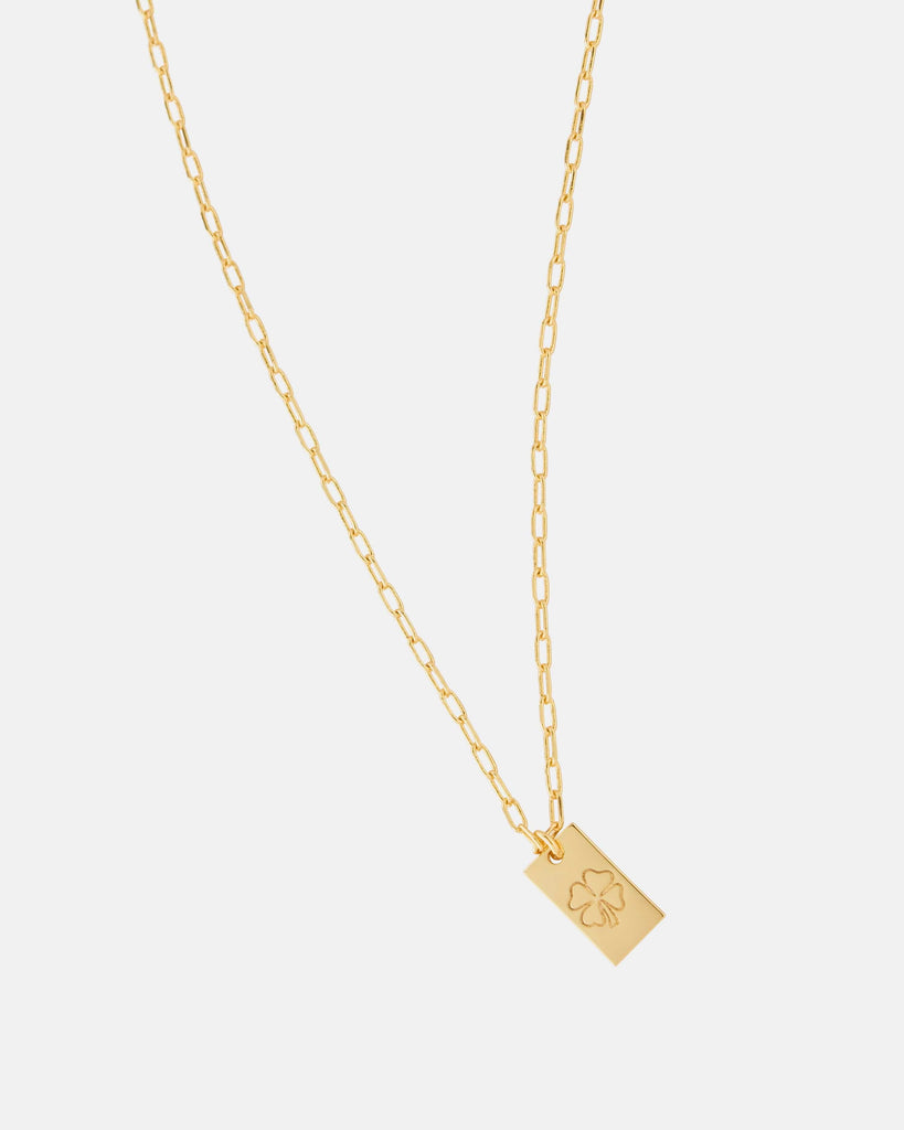 Gold necklace with four leaf clover on charm.