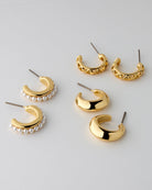 Set of gold and pearl earrings on a light gray background