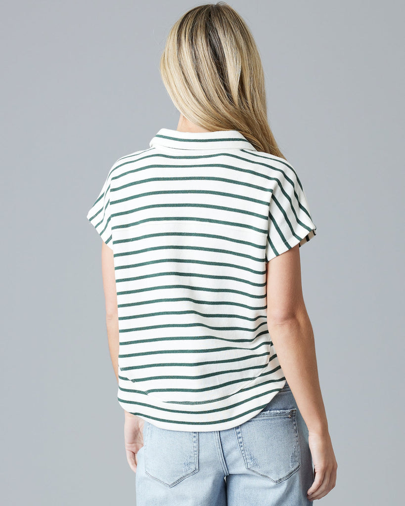 Woman in a green and white striped, short sleeve, v-neck with collar sweater