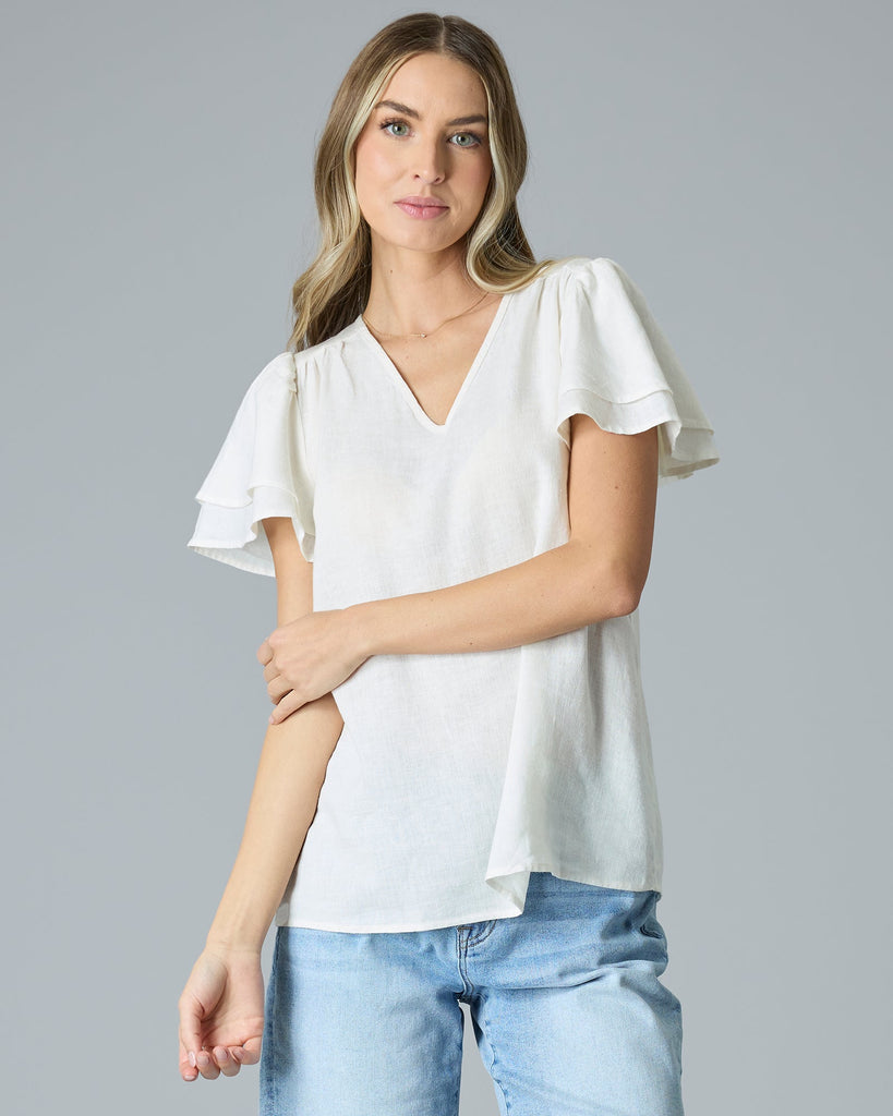 Woman in cream colored short sleeve, v-neck linen blouse